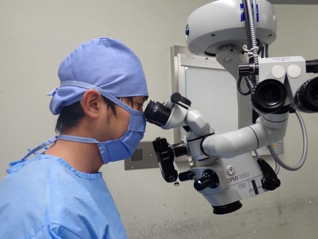 手術用顕微鏡を覗いて眼科手術を行う獣医師